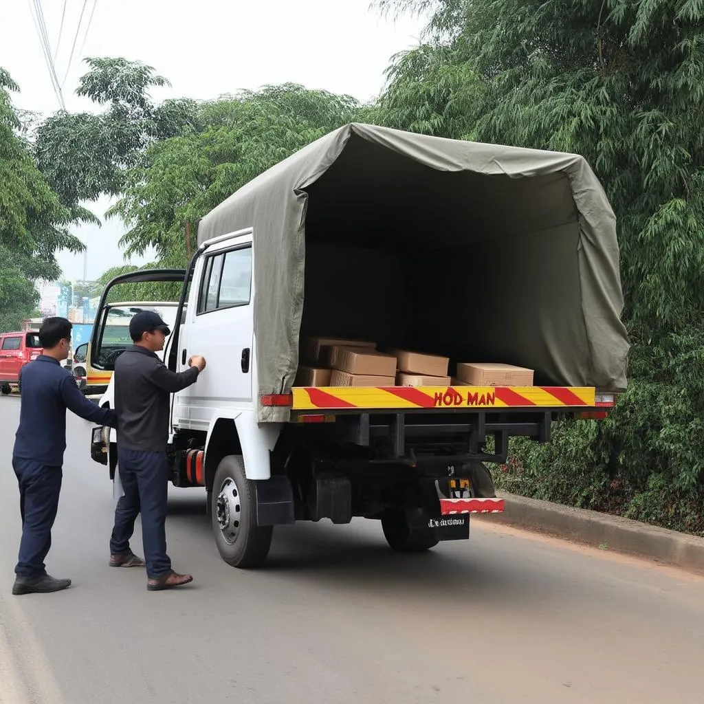 Tài xế đang vận chuyển hàng hóa lên xe tải Hoa Mai 1 tấn